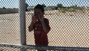 Nine-year-old Luis standing on the Mexican side of the border at Anapra, and talking through the fence with me and a friend. (Photo by Heath Haussamen)