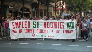 Protesters line the street in Donostia, Spain, on July 19. The large banner they are holding reads, "Employment Yes (Budget) Cuts No." (Joxemai via Wikimedia Commons)
