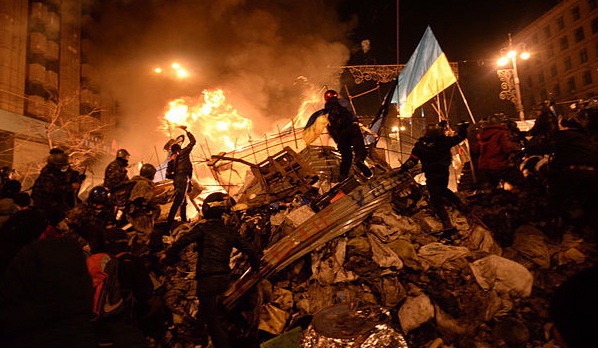 The state flag of Ukraine is carried by a protester to the heart of developing clashes in Kyiv, Ukraine, on Feb. 18, 2014 (Mstyslav Chernov via Wikimedia Commons)